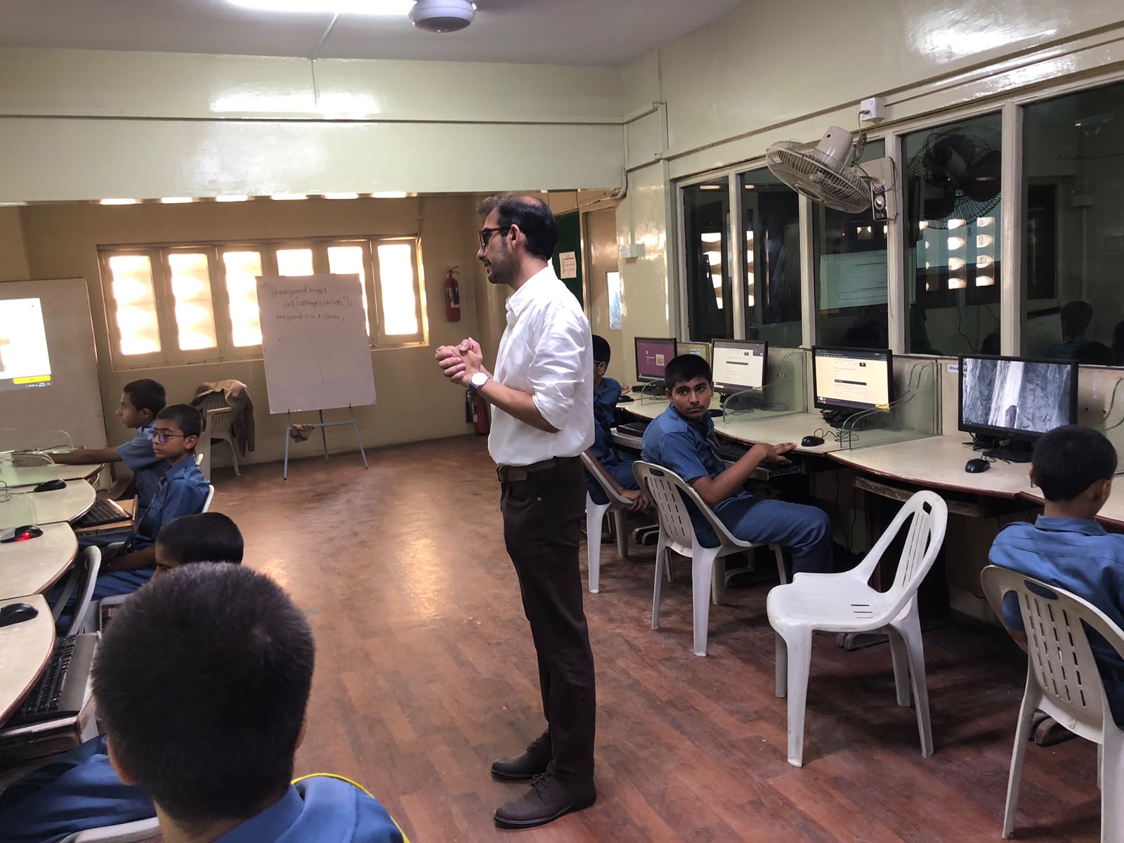 A facilitator speaking to students during a workshop session in a school computer lab